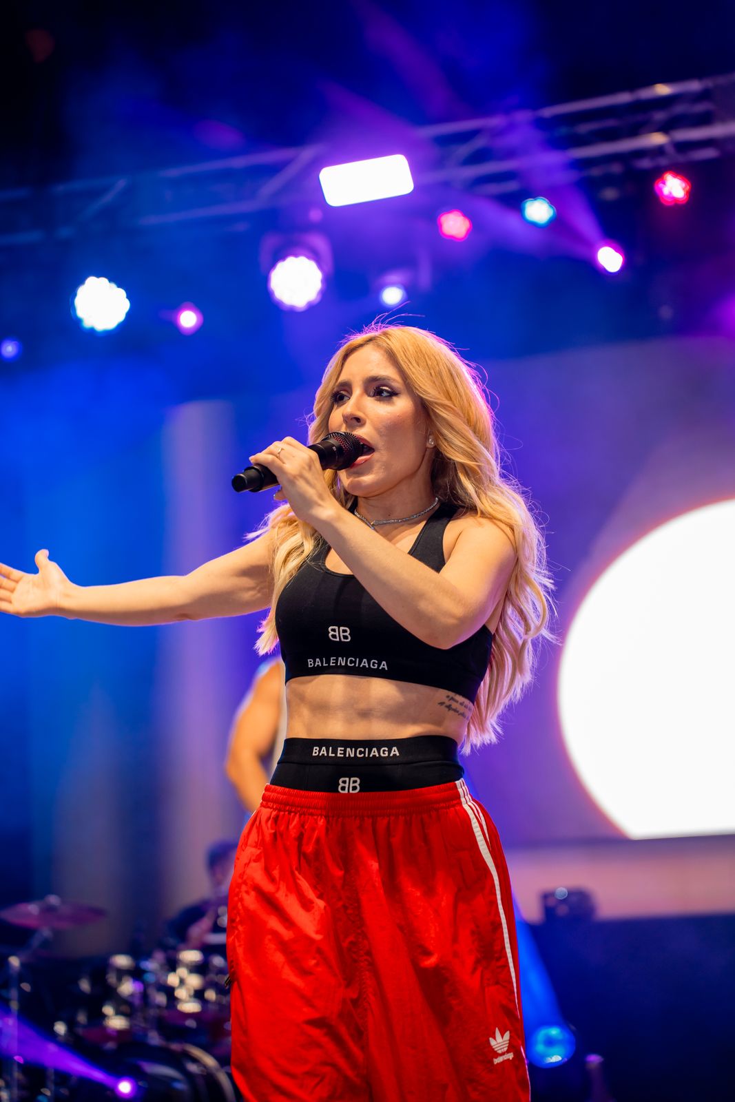 Vocalist on microphone under blue and magenta beams in front of a circular LED