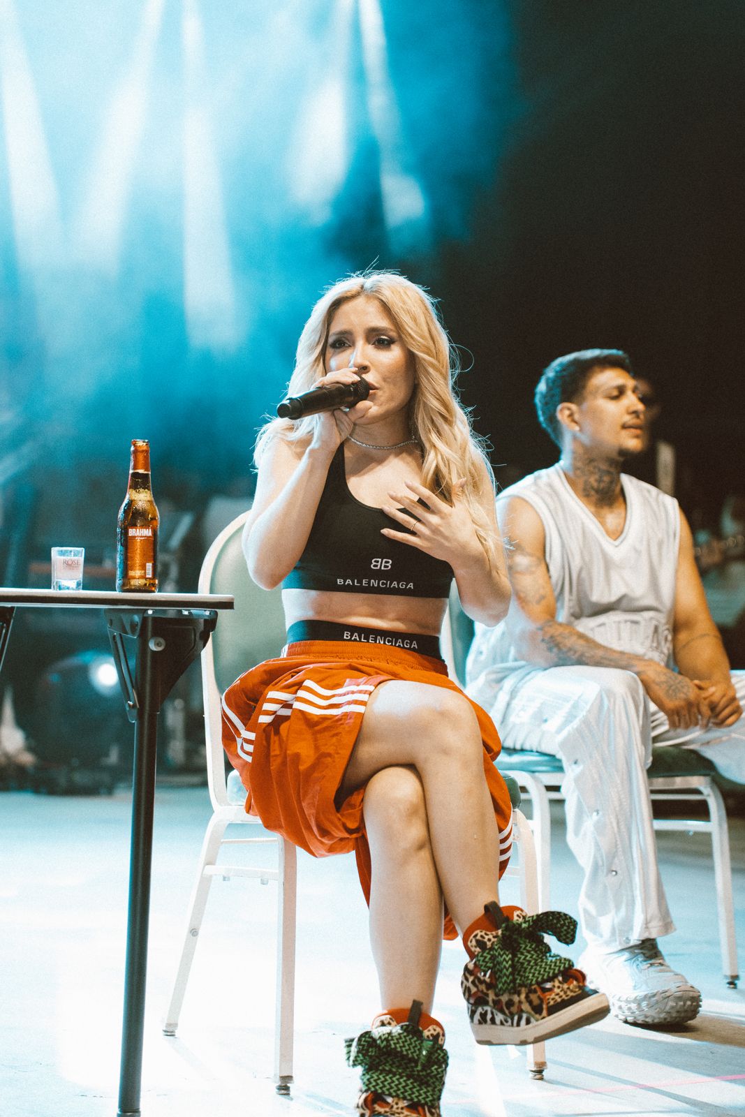 Vocalist on stage under blue beams with the band behind her