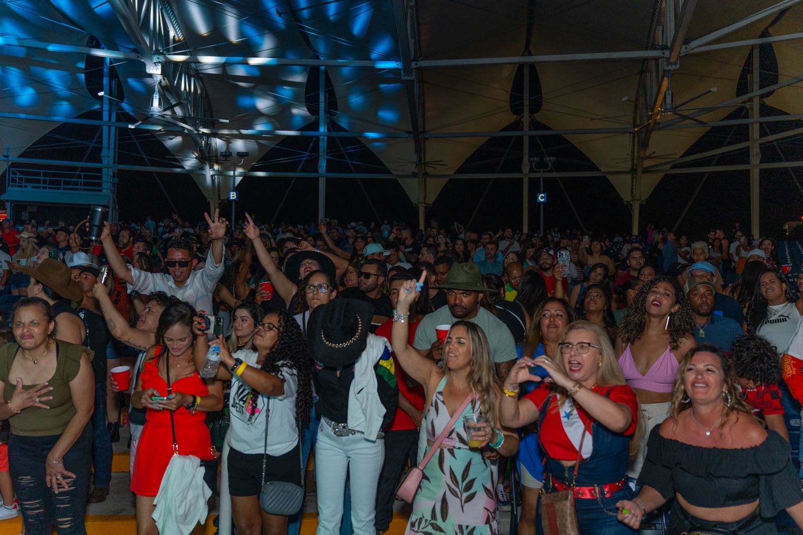 A full crowd with hands in the air under the venue roof