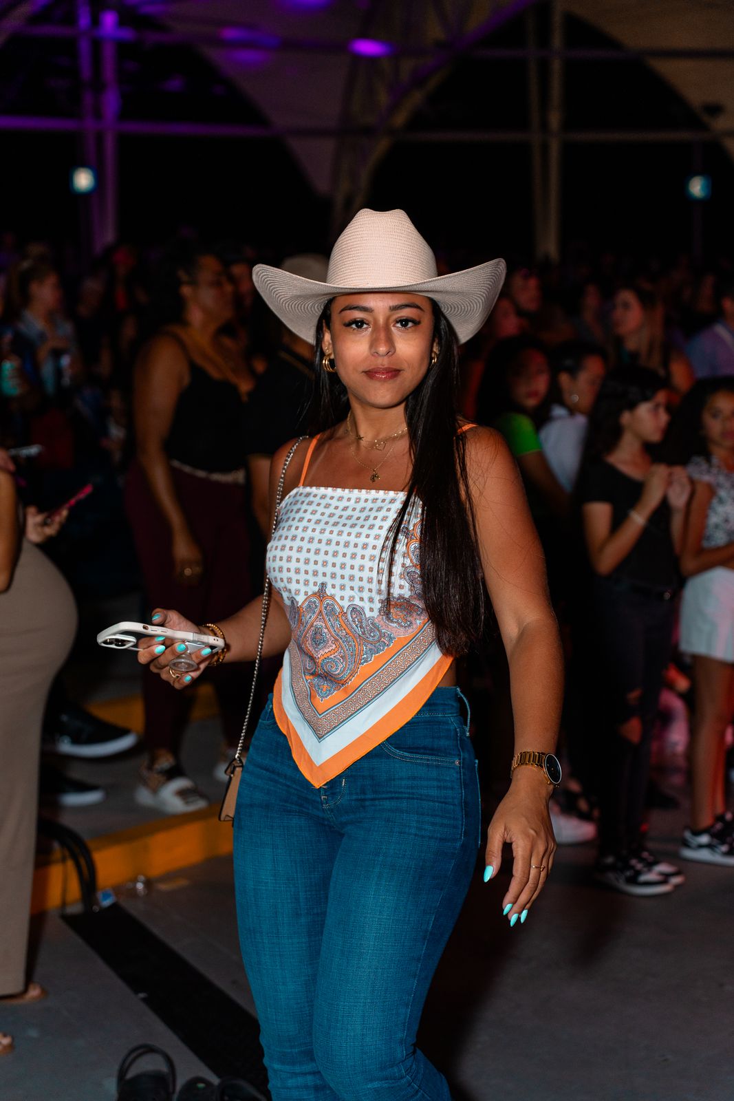 Guest in a cowboy hat on a crowded floor under purple light