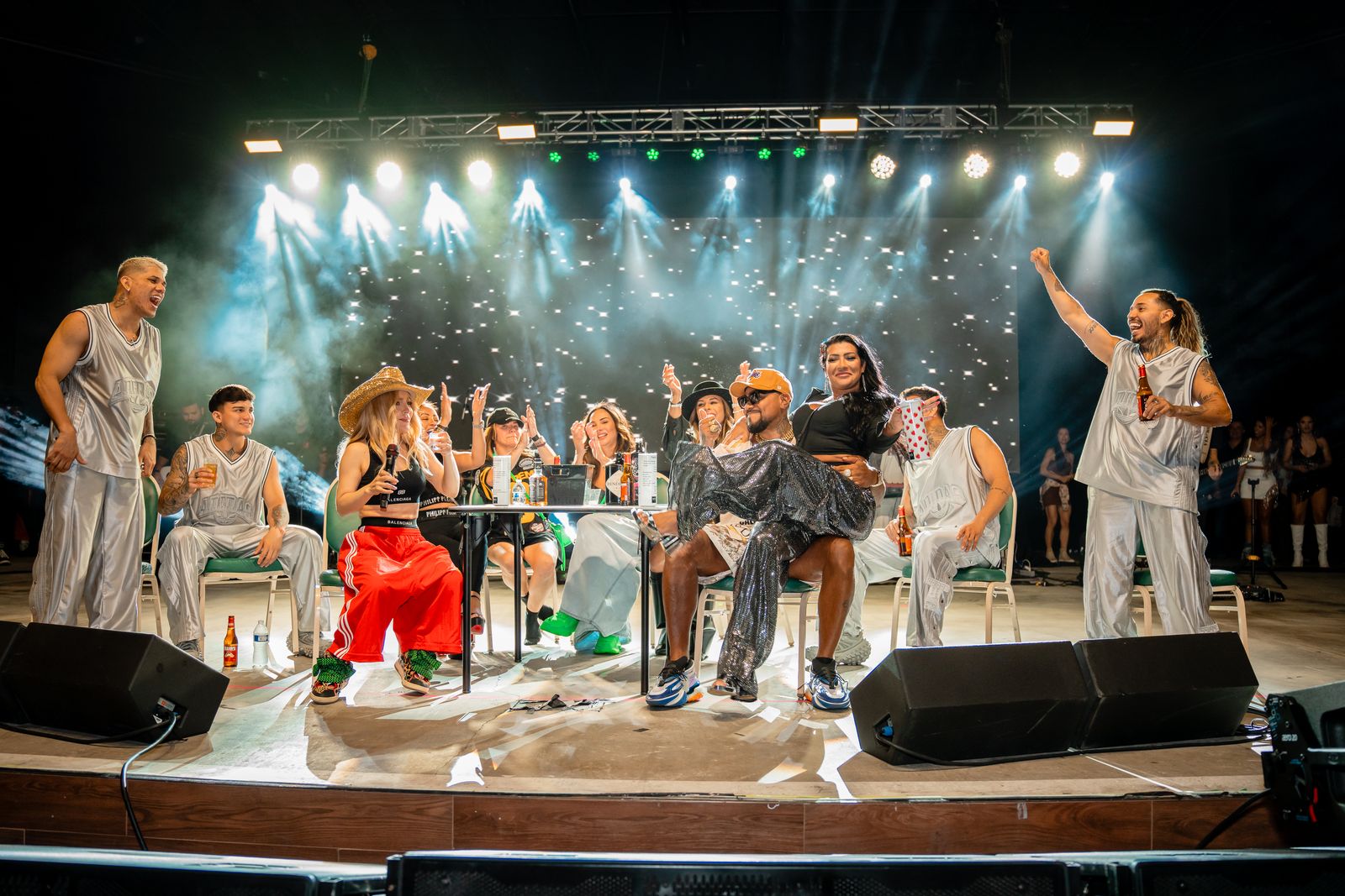 Wide view of the full stage build with truss, lighting rig, monitors and the cast performing